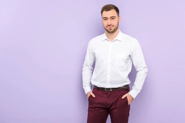 Чоловік у сорочці стоїть з руками в кишенях ізольовано на фіолетовому — стокове фото
