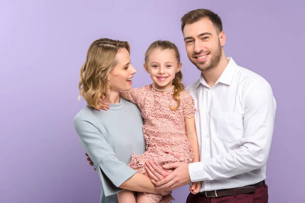 Adorable familia abrazando con hija en violeta fondo - foto de stock