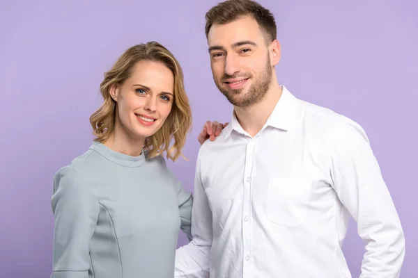 Junger Mann und Frau lächeln isoliert auf violett — Stockfoto