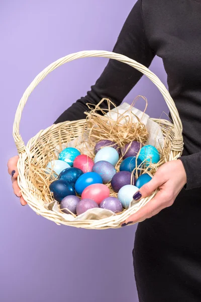 Woman holding Easter eggs in basket isolated on violet — Stock Photo
