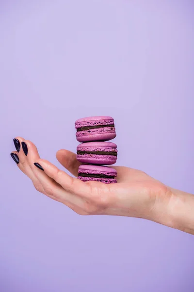 Femme tenant des macarons isolés sur violet — Photo de stock