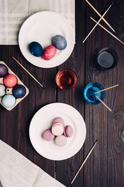 Ostereier und Macarons auf Teller auf Holztisch — Stockfoto