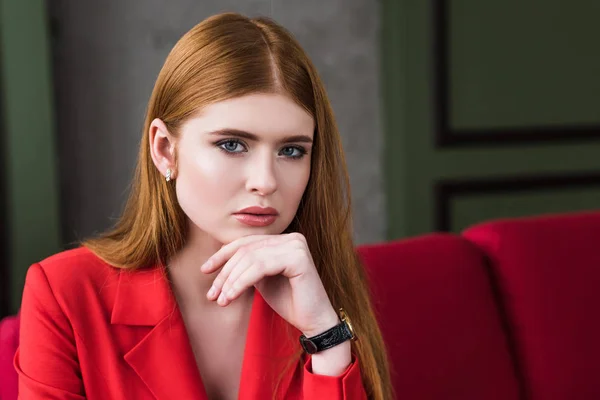 Atractiva mujer joven con estilo con reloj de pulsera posando en chaqueta roja - foto de stock
