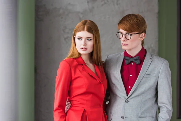 Young male fashion model in eyeglasses and bow tie holding girlfriend waist — Stock Photo