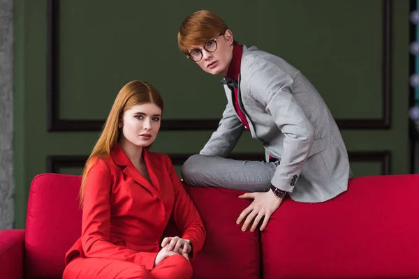 Pareja de joven modelo vestida con trajes en el sofá — Stock Photo