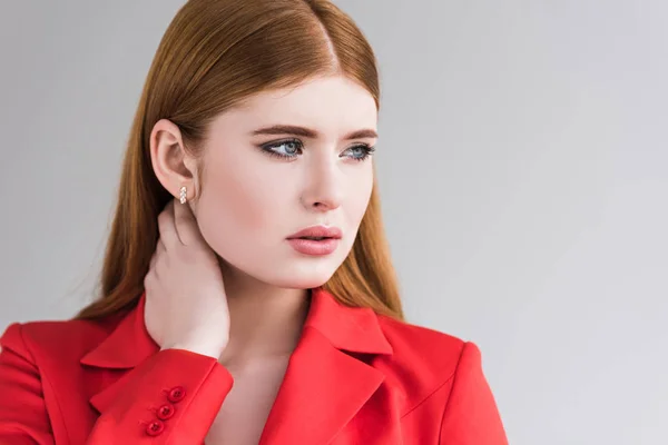 Portrait of young female fashion model with earrings in jacket isolated on grey — Stock Photo