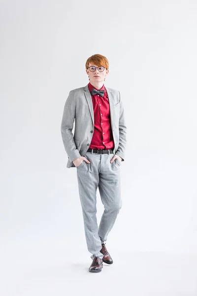 Young male fashion model in eyeglasses dressed in suit isolated on grey — Stock Photo