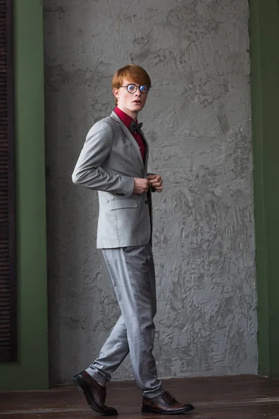 Jeune mannequin masculin en lunettes habillé en costume gris — Photo de stock