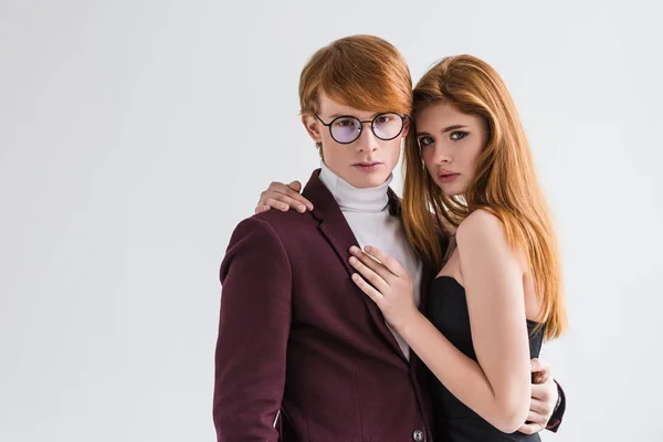 Молодой мужчина модель в очках держит свою девушку изолированной на серый — стоковое фото