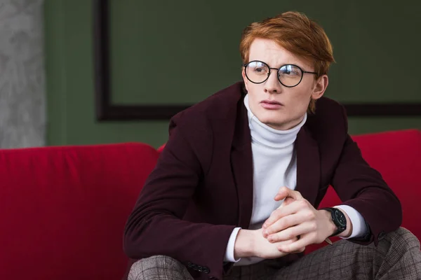 Junges männliches Modemodel mit Brille sitzt auf Couch — Stockfoto