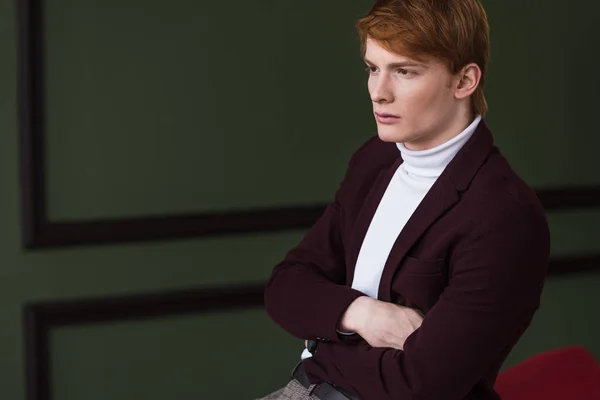 Side view of male model in jacket sitting on couch — Stock Photo