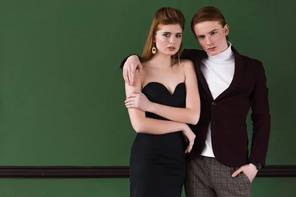 Young male fashion model holding girlfriend shoulder in front of wall — Stock Photo