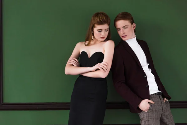 Elegante pareja joven vestida con ropa formal frente a la pared verde - foto de stock