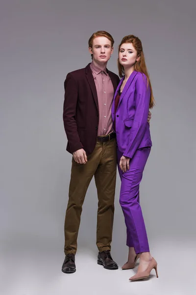 Pareja de elegantes modelos jóvenes vestidos con ropa formal aislados en gris - foto de stock