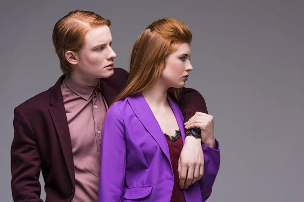 Vista lateral de jovens modelos de moda casal isolado em cinza — Fotografia de Stock