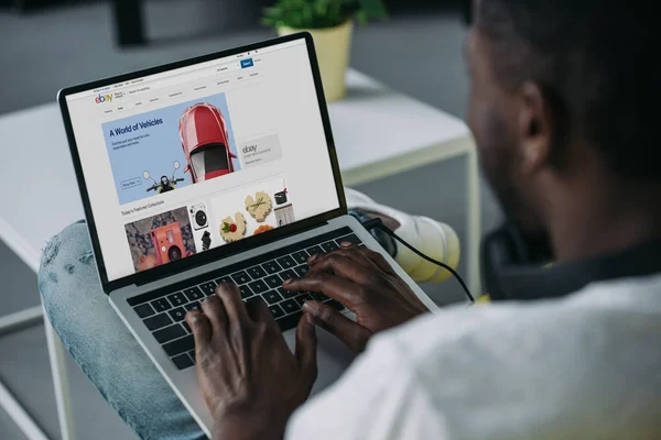 Tiro recortado do homem americano africano novo usando o portátil com o Web site de ebay na tela — Fotografia de Stock