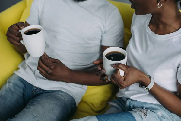 Обрезанный снимок молодой африканской американской пары, держащей чашки кофе дома — стоковое фото