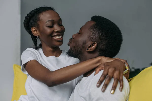 Schöne junge afrikanisch-amerikanische Paar umarmt und lächelt einander zu Hause — Stockfoto