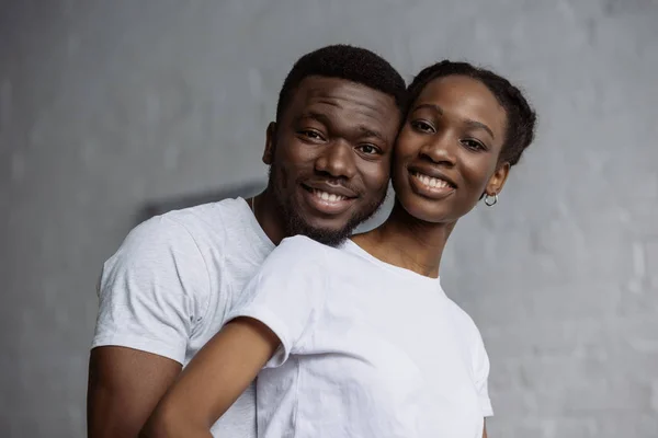 Щаслива молода афроамериканська пара в білих футболках посміхається на камеру — стокове фото