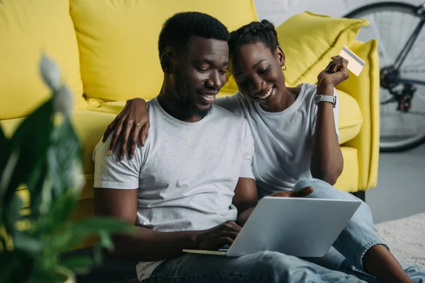 Heureux jeune couple afro-américain avec ordinateur portable et achats par carte de crédit en ligne ensemble — Photo de stock