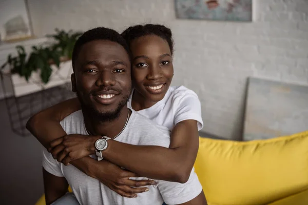 Heureux jeune couple afro-américain étreignant et souriant à la caméra — Photo de stock