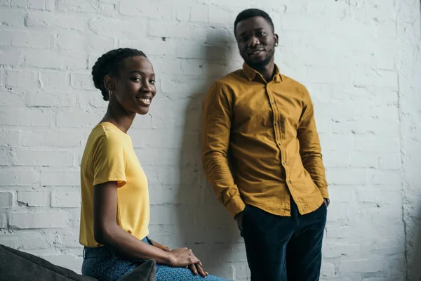 Bella giovane coppia afroamericana in camicie gialle sorridente alla macchina fotografica — Foto stock