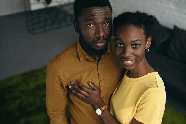 Vue grand angle de beau jeune couple afro-américain debout ensemble et regardant la caméra à la maison — Photo de stock