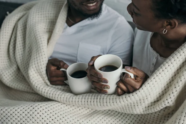 Plan recadré de heureux jeune couple afro-américain boire une boisson chaude ensemble à la maison — Photo de stock