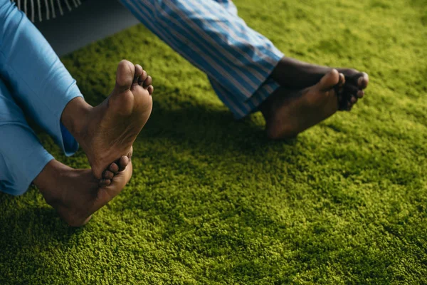 Close-up partial view of barefoot african american couple in pajamas spending time together at home — Stock Photo