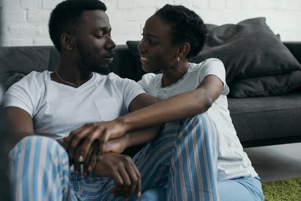 Красивая молодая африканская пара в пижаме, улыбающаяся друг другу дома — стоковое фото