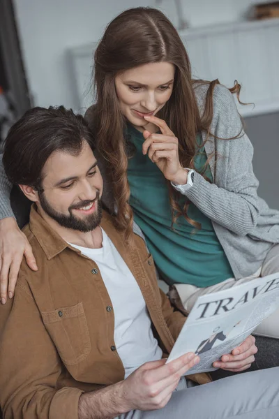 Attractive couple reading travel newspaper and planning trip at home — Stock Photo