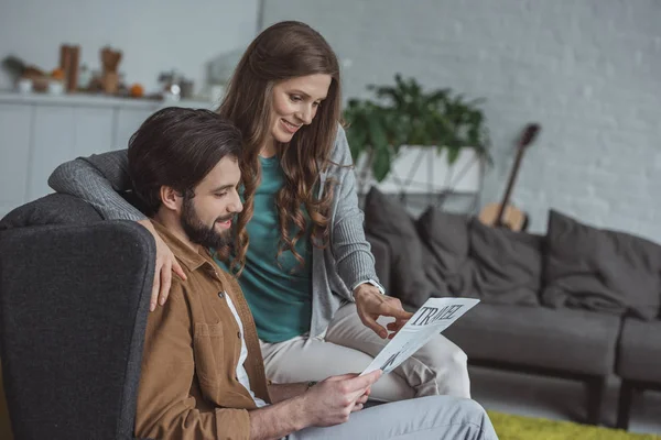 Side view of attractive couple reading travel newspaper and planning trip at home — Stock Photo