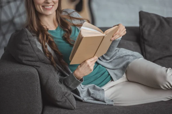 Abgeschnittenes Bild einer lächelnden Frau, die zu Hause Buch liest — Stockfoto