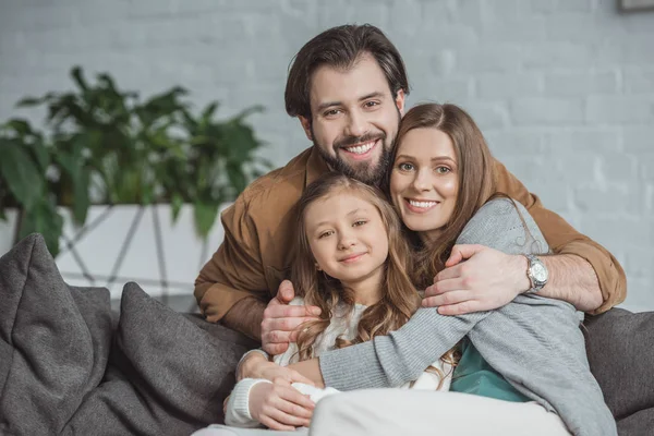 Happy parents and daughter hugging and looking at camera — Stock Photo