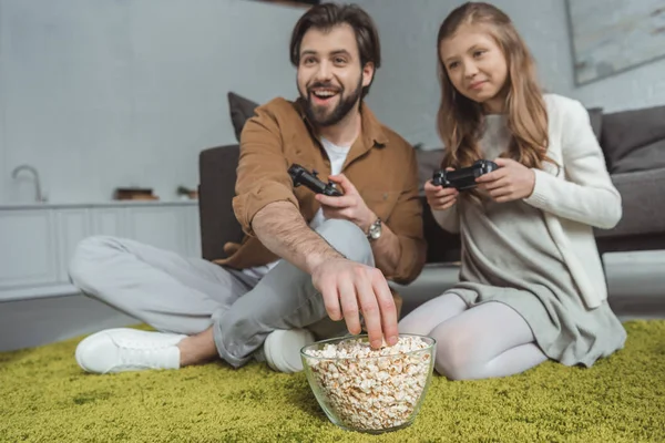 Pai jogar vídeo game com filha e comer pipocas — Fotografia de Stock