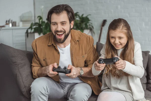 Feliz padre e hija jugando videojuegos en casa - foto de stock