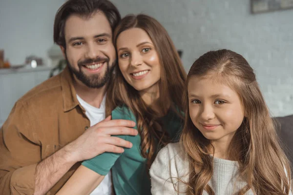 Lächelnde Eltern und Tochter schauen zu Hause in die Kamera — Stockfoto