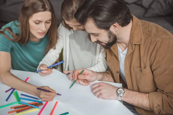 Vista ad alto angolo di genitori e figlia che disegnano con pennarelli — Foto stock