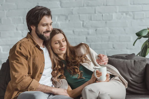 Boyfriend hugging girlfriend with cup of coffee at home — Stock Photo