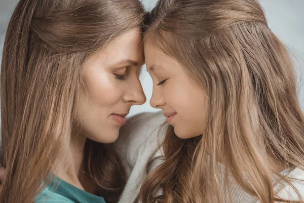 Seitenansicht von Mutter und Tochter, die sich zu Hause mit Stirn berühren — Stockfoto
