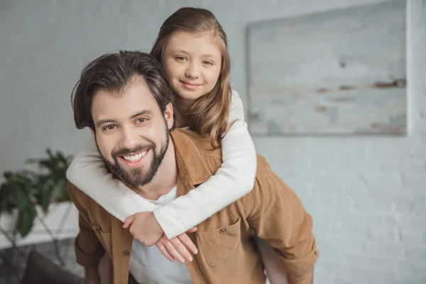 Padre sorridente che dà a cavalluccio a figlia a casa — Foto stock