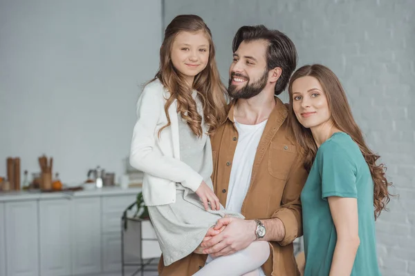 Smiling parents and daughter standing together in kitchen — Stock Photo