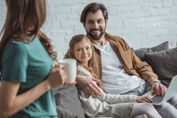 Father hugging daughter and looking at mother with cup of coffee — Stock Photo