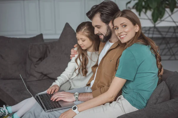 Parents and daughter using laptop on sofa at home — Stock Photo