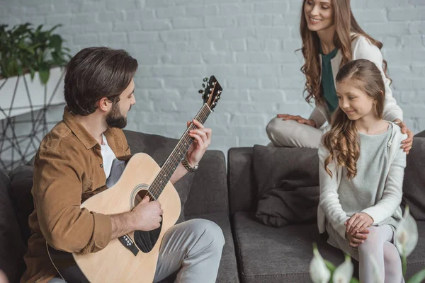Pai tocando guitarra para filha e esposa em casa — Fotografia de Stock