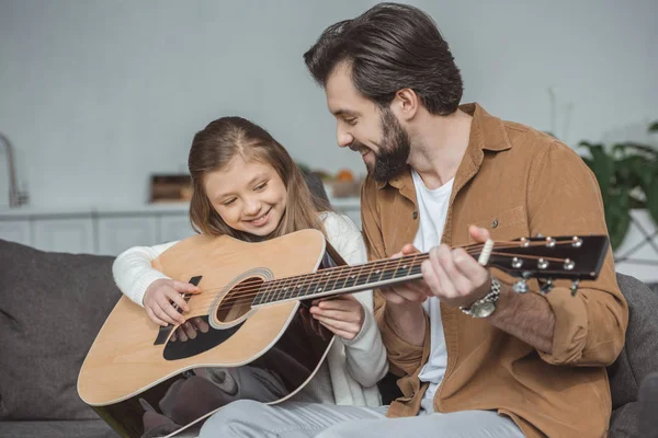 Padre feliz enseñando hija tocando la guitarra acústica - foto de stock