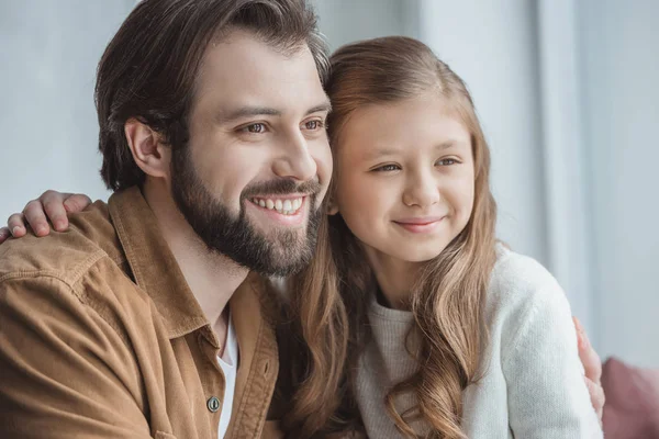 Smiling father and daughter looking away at window — Stock Photo