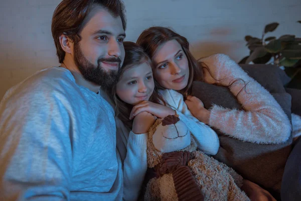 Parents et fille regardant un film sur le canapé en soirée — Photo de stock