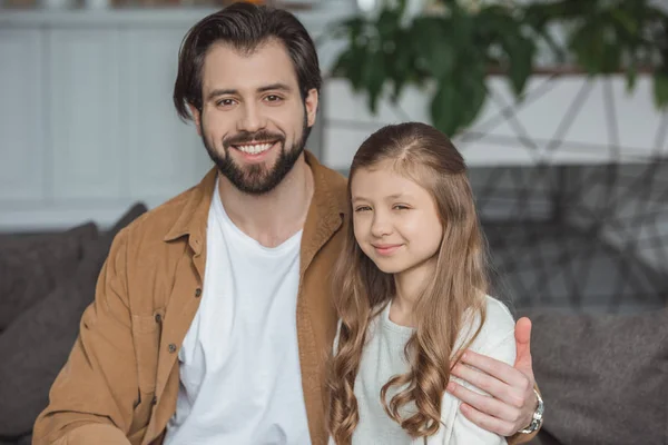 Lächelnder Vater umarmt Tochter und blickt in die Kamera — Stockfoto