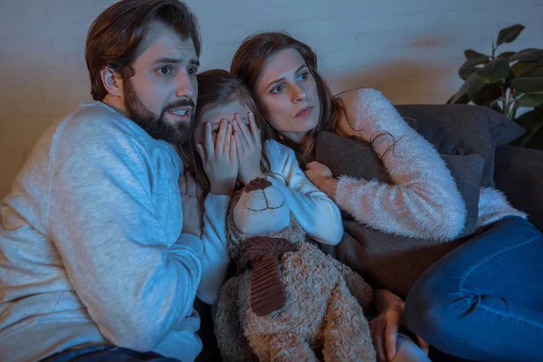 Genitori e figlia guardando film horror in serata a casa — Foto stock